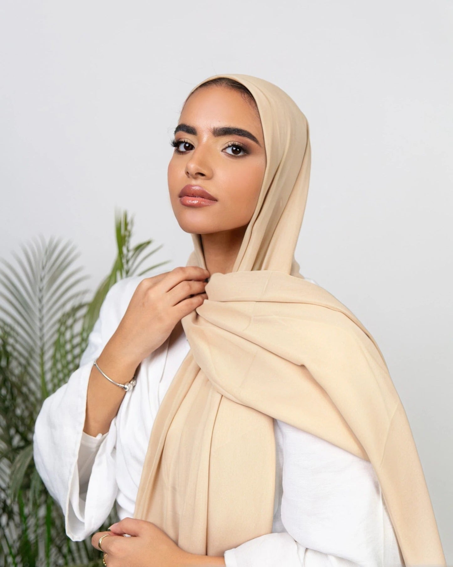 A woman wearing a pink instant hijab with an inner Syrian bandana, paired with a white shirt.